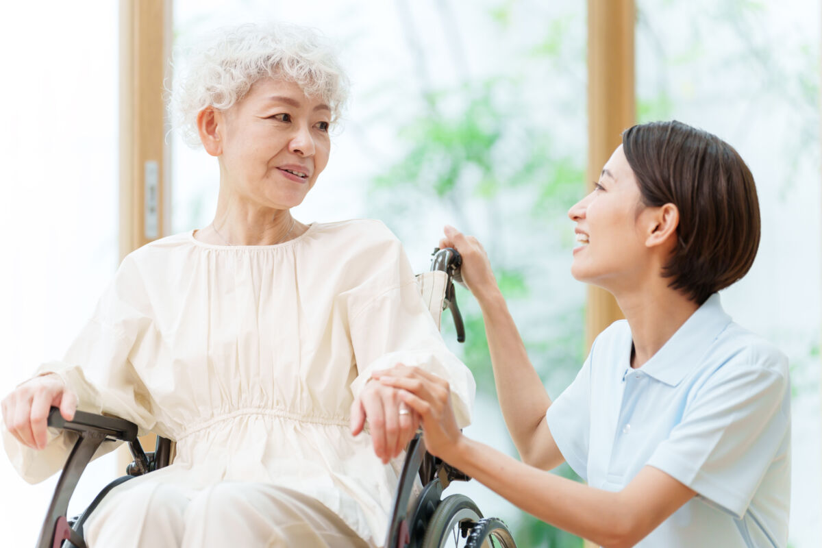 車椅子に乗った女性をサポートする介護士